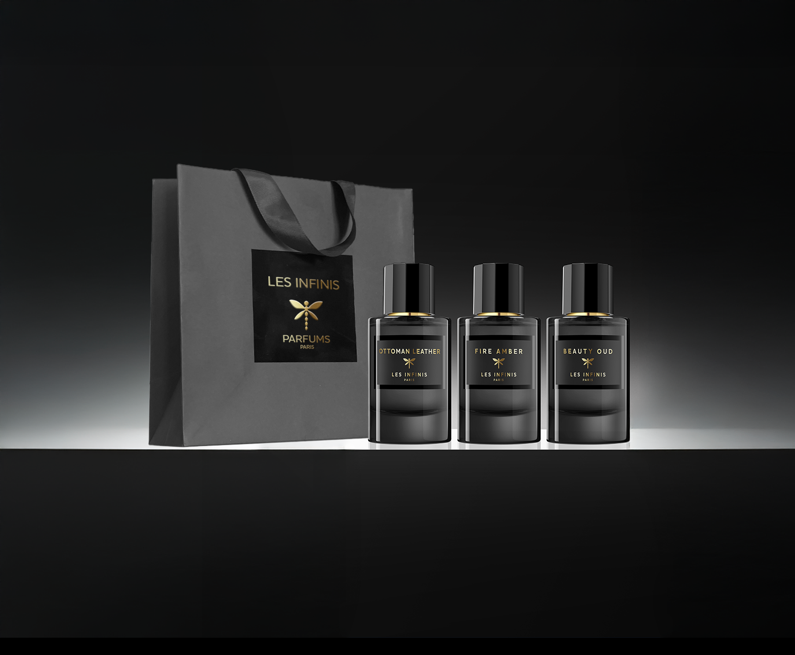 Three perfume bottles and a black gift bag with 'LES INFINIS PARFUMS' branding on a dark background.