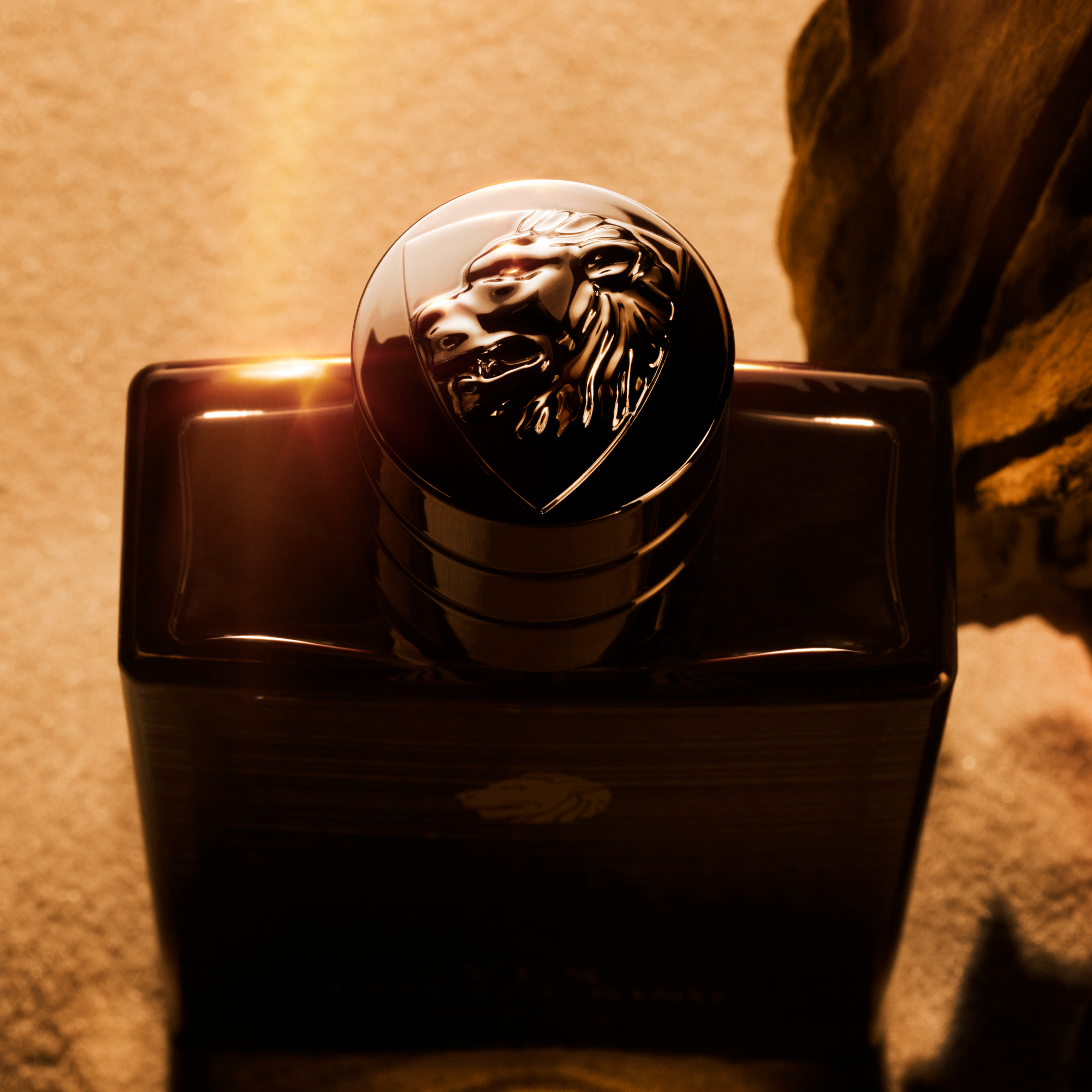 Black perfume bottle with a lion emblem on a textured surface